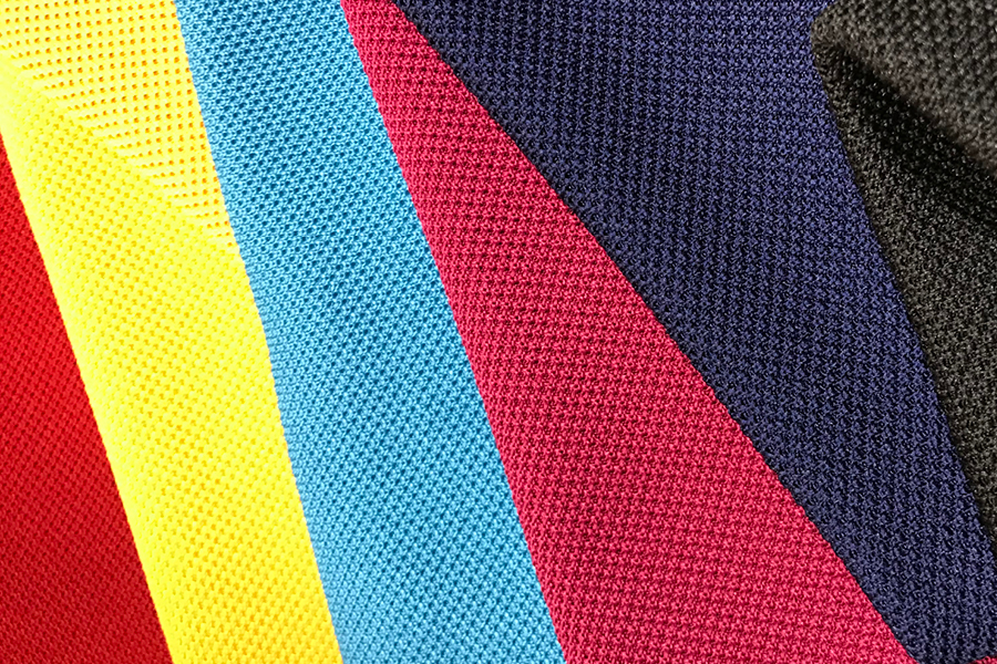 Close-up of DreamWeave fabric swatches in red, yellow, blue, pink, navy, and black arranged in overlapping diagonal panels.