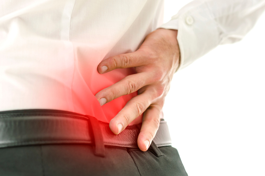 Person in white shirt holding lower back with hand showing red highlighting indicating pain or discomfort in lumbar area.