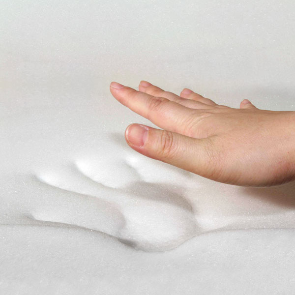 Hand pressing into soft memory foam, leaving a temporary indentation.