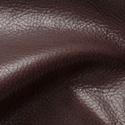 Close-up of textured brown leather material with natural grain patterns and soft folds.