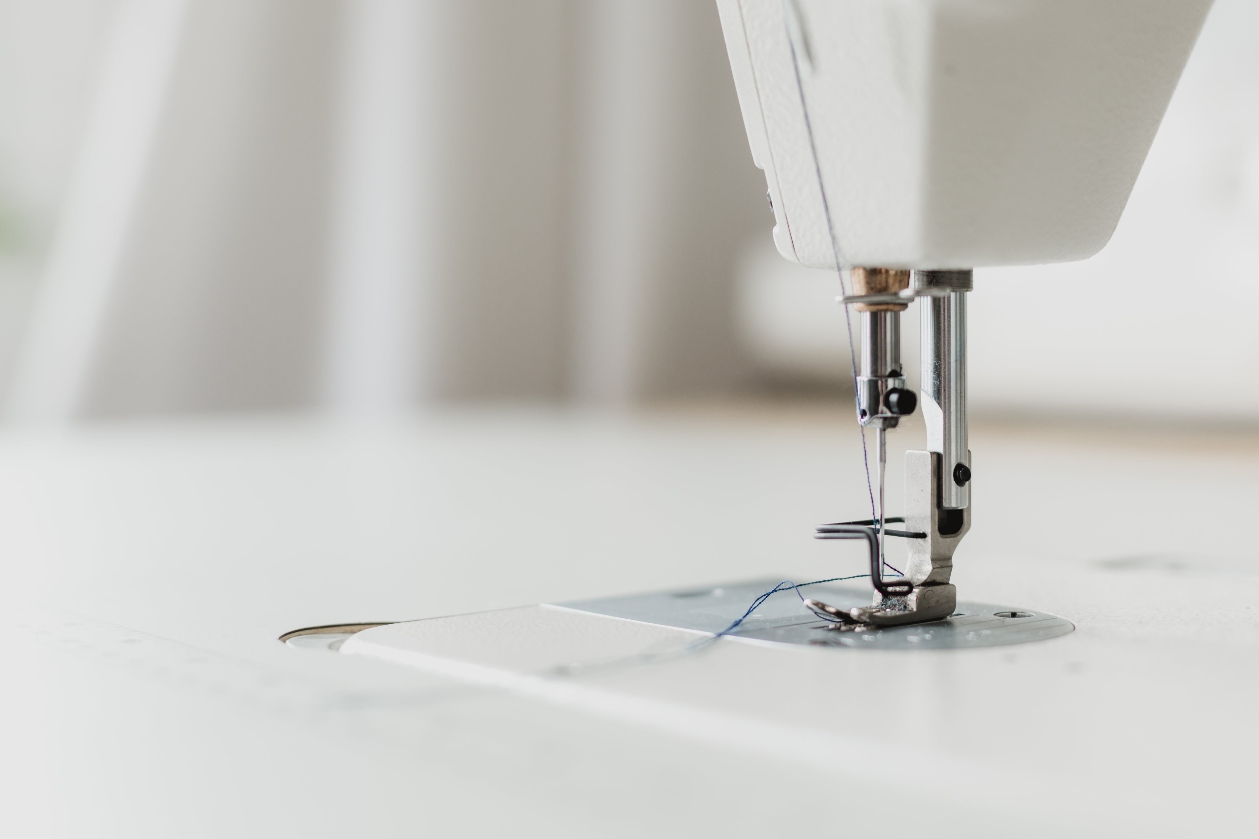 Close-up of a sewing machine needle and presser foot threaded and ready for stitching.