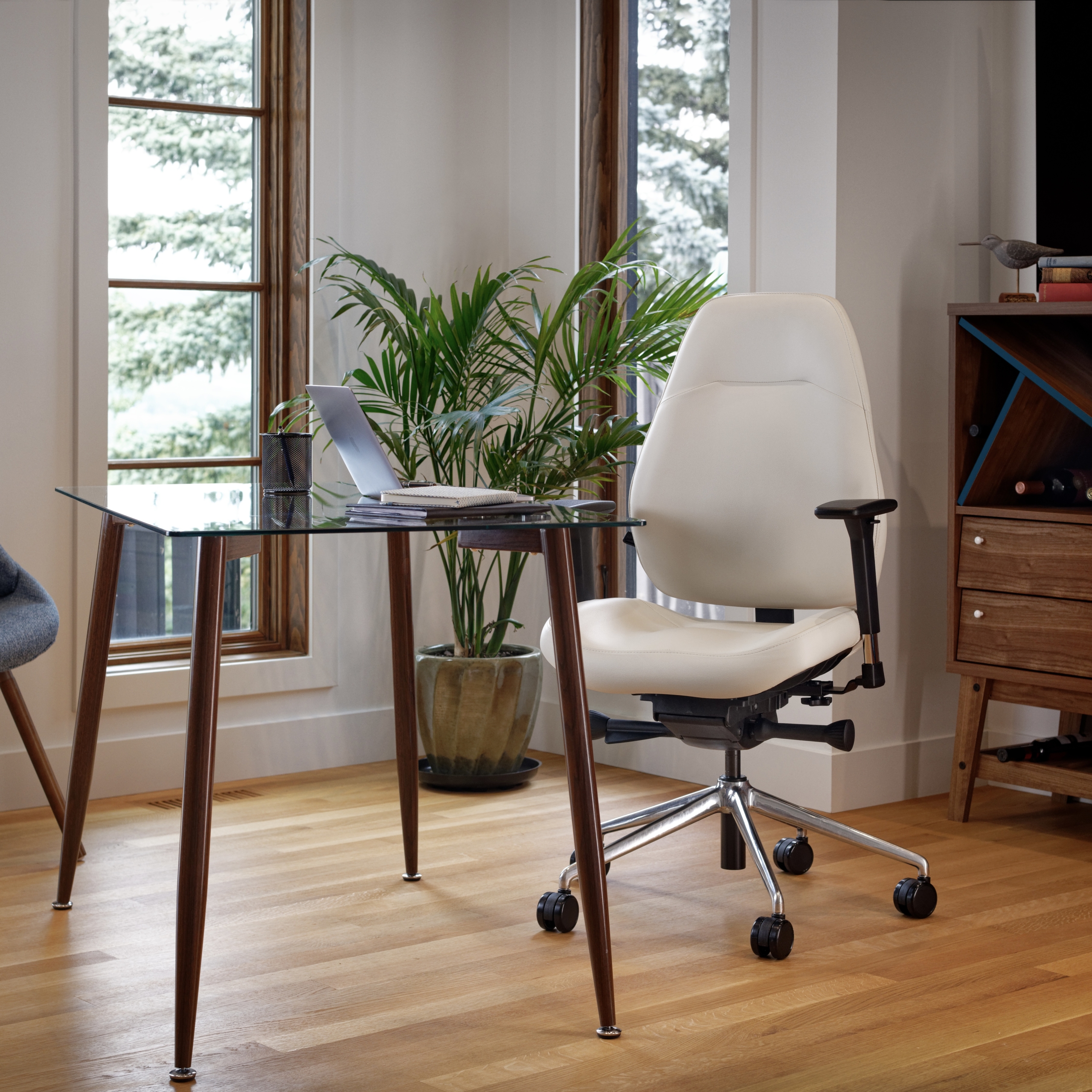 LIFEFORM® Palisades Conference Mid Back Chairs A cream-coloured ergonomic office chair with a polished chrome base sits at a glass-topped desk in a bright, modern home office with hardwood floors.