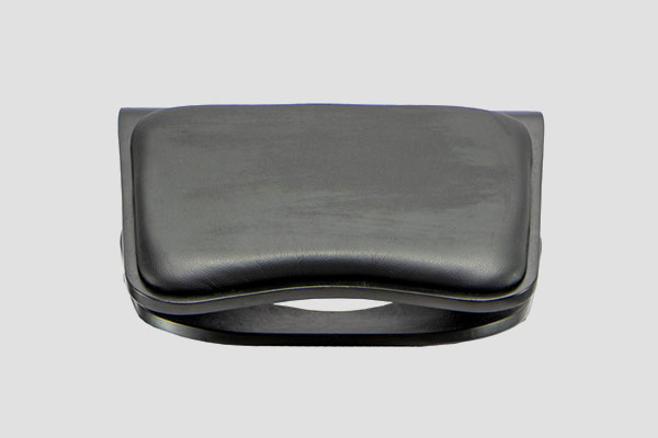 Black ergonomic footrest with curved cushioned top and arched base design shown on grey background.