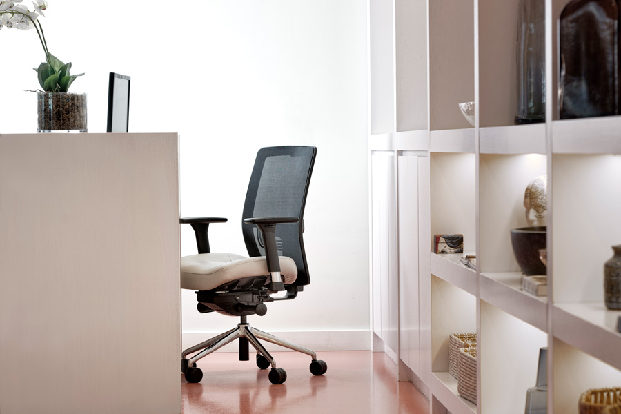 Modern ergonomic office chair with mesh back and beige seat beside white shelving unit in minimalist workspace.